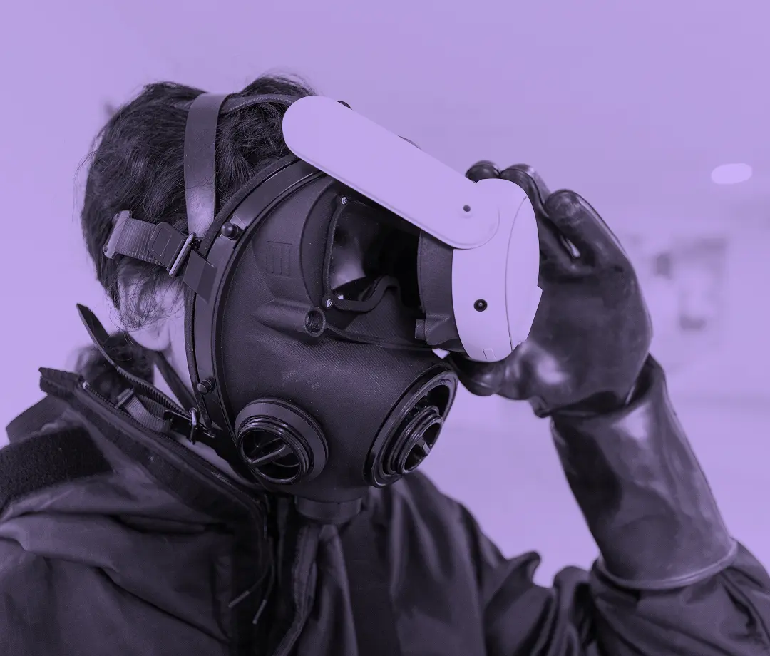 Operator in CBRN protective suit holding a Almost Real VR headset
