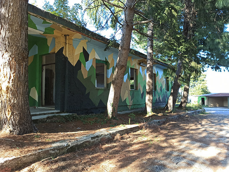Base Calvarina, former NATO base with camouflage-painted buildings surrounded by trees